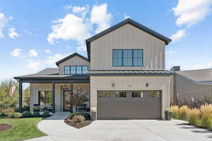 Modern farmhouse style home featuring board and batten siding, a garage, covered porch, driveway, and a shingled roof
