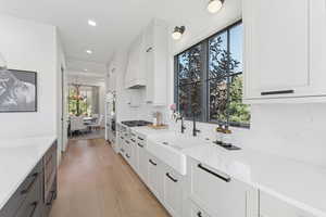 Kitchen featuring dual tone cabinetry, light wood-style flooring, light stone counters, stainless steel gas cooktop, and recessed lighting