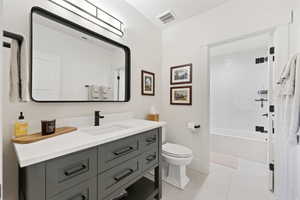 Bathroom with vanity, shower / bathtub combination, and light tile patterned flooring