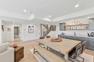 Dining space featuring light wood-style flooring, bar with sink, and recessed lighting