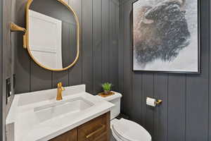 Half bath with vanity and wooden walls