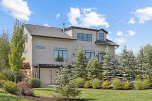 Rear view of house with roof with shingles, a yard, and an attached garage