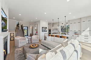Living area with a lit fireplace, light wood finished floors, and recessed lighting