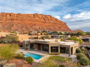 Rear view of house with stucco siding, an outdoor pool, a mountain view, and a patio area