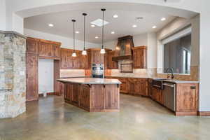 Kitchen with wood finish cabinetry, backsplash, a kitchen island, and decorative light fixtures