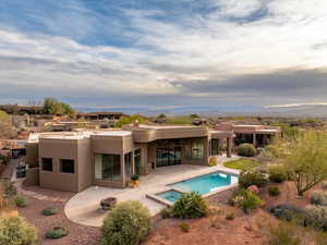 Rear view of house featuring a patio, stucco siding, a pool with connected hot tub, and a mountain view