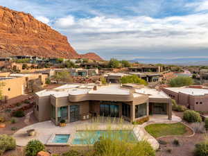 Back of house featuring stucco siding, a sunroom, a mountain view, and a patio