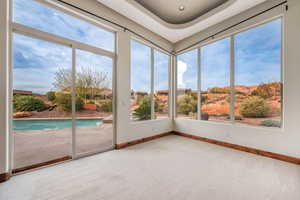 Unfurnished sunroom featuring carpet floors and baseboards