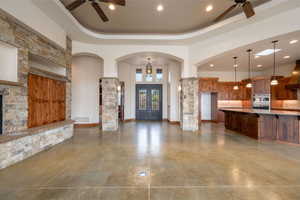 Entryway with a ceiling fan, a high tray ceiling, arched walkways, and recessed lighting