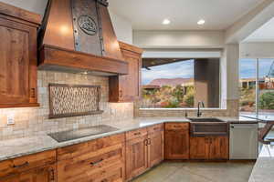 Kitchen featuring light stone countertops, wood finish cabinetry, stainless steel dishwasher, and recessed lighting