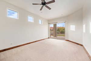 Carpeted spare room with plenty of natural light and ceiling fan