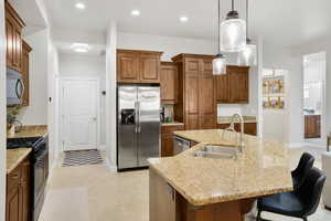 Kitchen with stainless steel appliances, wood finish cabinetry, and light stone counters