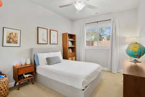 Bedroom with a ceiling fan and light colored carpet