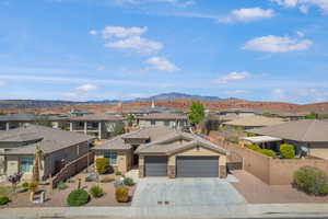 View of front of house with a residential view, stone siding, an attached garage, concrete driveway, and a gate
