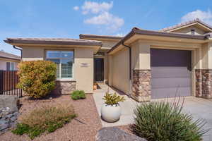 View of front of house with stone siding, a garage, stucco siding, and concrete driveway