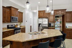 Kitchen with stainless steel appliances, a breakfast bar area, and light stone counters