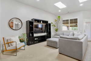 Living area featuring a skylight, recessed lighting, and light carpet