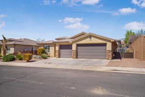 View of front facade featuring stone siding, an attached garage, stucco siding, a gate, and concrete driveway