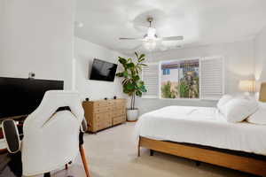 Carpeted bedroom featuring a ceiling fan and an office area