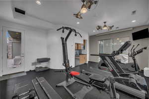 Exercise room with dark rubber floors, recessed lighting, and ceiling fan