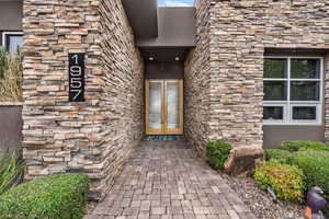 Entrance to property with stucco siding and stone siding
