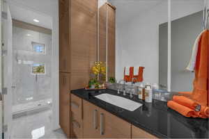 Bathroom with vanity, a marble finish shower, and recessed lighting