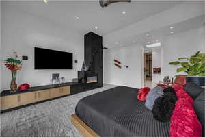Bedroom featuring light colored carpet, a glass covered fireplace, and recessed lighting