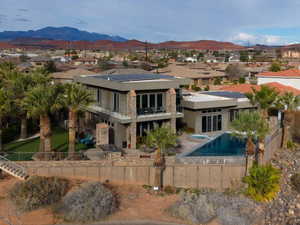 Back of house featuring a fenced backyard, solar panels, a balcony, and stucco siding