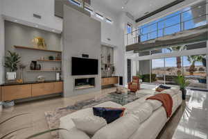Living area featuring a high ceiling, recessed lighting, and a glass covered fireplace