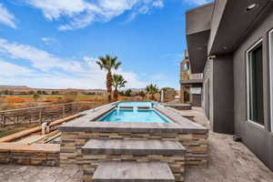 View of swimming pool featuring patio surround and an in-ground hot tub