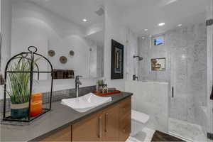 Bathroom with vanity, a marble finish shower, and recessed lighting