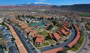 Aerial view of property and surrounding area featuring a mountainous background and nearby suburban area