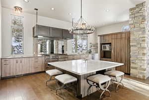Kitchen with a breakfast bar, hanging light fixtures, appliances with stainless steel finishes, a center island with sink, and light wood finished floors