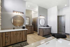 Full bathroom with two vanities, light wood finished floors, and recessed lighting