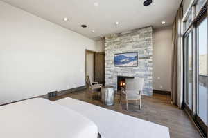Bedroom featuring a stone fireplace, recessed lighting, dark wood finished floors, and access to outside