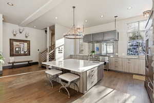 Kitchen with decorative light fixtures, dark wood finished floors, recessed lighting, a kitchen bar, and high end stainless steel range oven