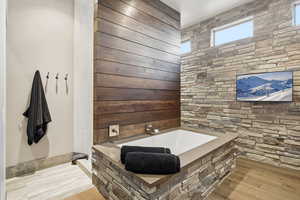 Full bathroom featuring a garden tub and light wood-style floors