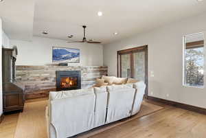 Living area with recessed lighting, a glass covered fireplace, light wood finished floors, and ceiling fan