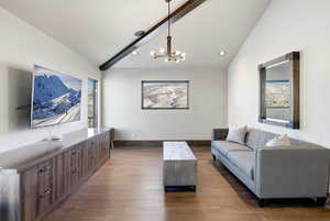 Living room with a chandelier, dark wood finished floors, healthy amount of natural light, recessed lighting, and high vaulted ceiling