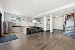 Bar area with stairway, pendant lighting, freestanding refrigerator, open shelves, and light wood-style floors