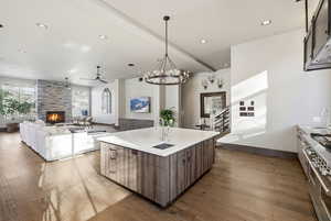 Kitchen featuring open floor plan, recessed lighting, a fireplace, range with two ovens, and beam ceiling