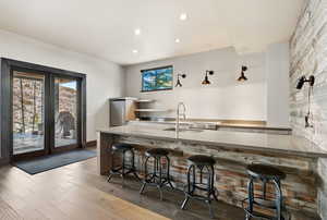 Kitchen featuring open shelves, a breakfast bar, plenty of natural light, light wood finished floors, and recessed lighting