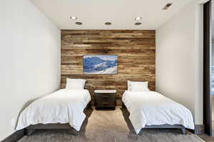 Bedroom featuring wooden walls, an accent wall, carpet flooring, and recessed lighting