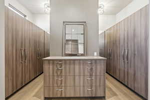 Walk in closet with light wood-style floors