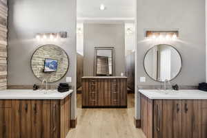 Bathroom with two vanities and light wood-style flooring