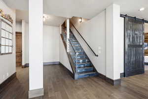 Stairs featuring a barn door and wood finished floors