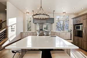 Kitchen featuring a breakfast bar area, an island with sink, premium appliances, recessed lighting, and light wood-type flooring