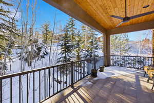 Snow covered deck with ceiling fan, a patio area, and a mountain view