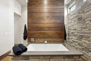 Full bathroom featuring a garden tub and wooden walls