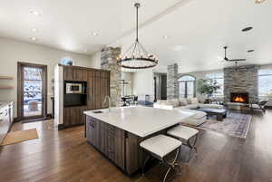 Kitchen featuring dark brown cabinetry, a chandelier, a kitchen breakfast bar, a kitchen island with sink, and recessed lighting